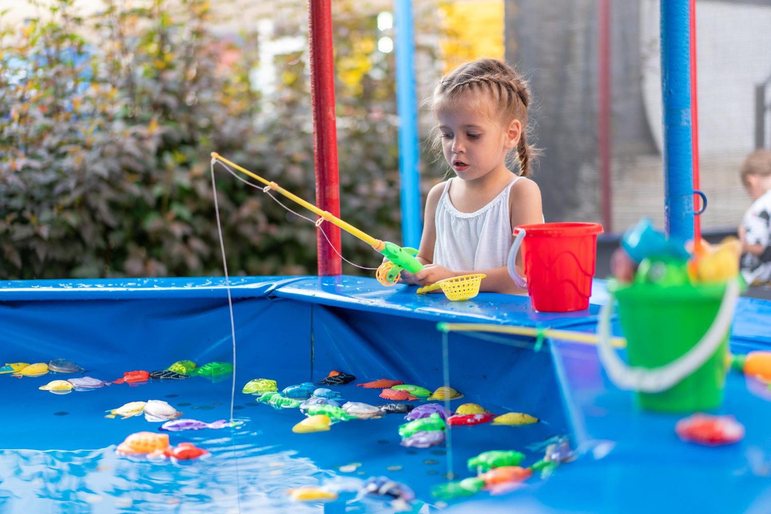 como limpar piscina de plástico: criança brincando de pescar brinquedos na piscina