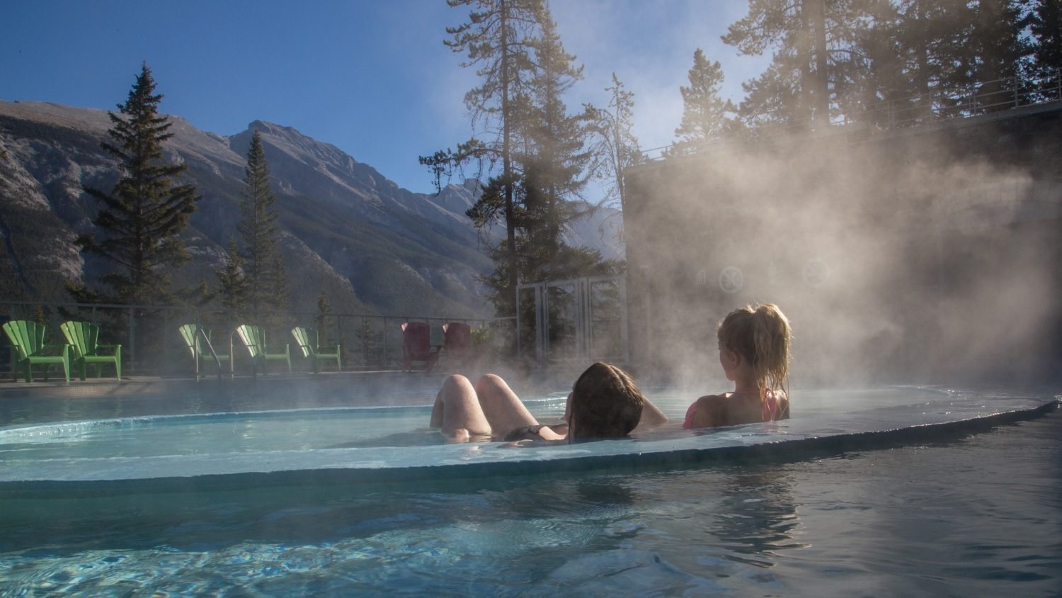 piscina aquecida no inverno, duas moças na piscina sentadas e olhando as montanhas