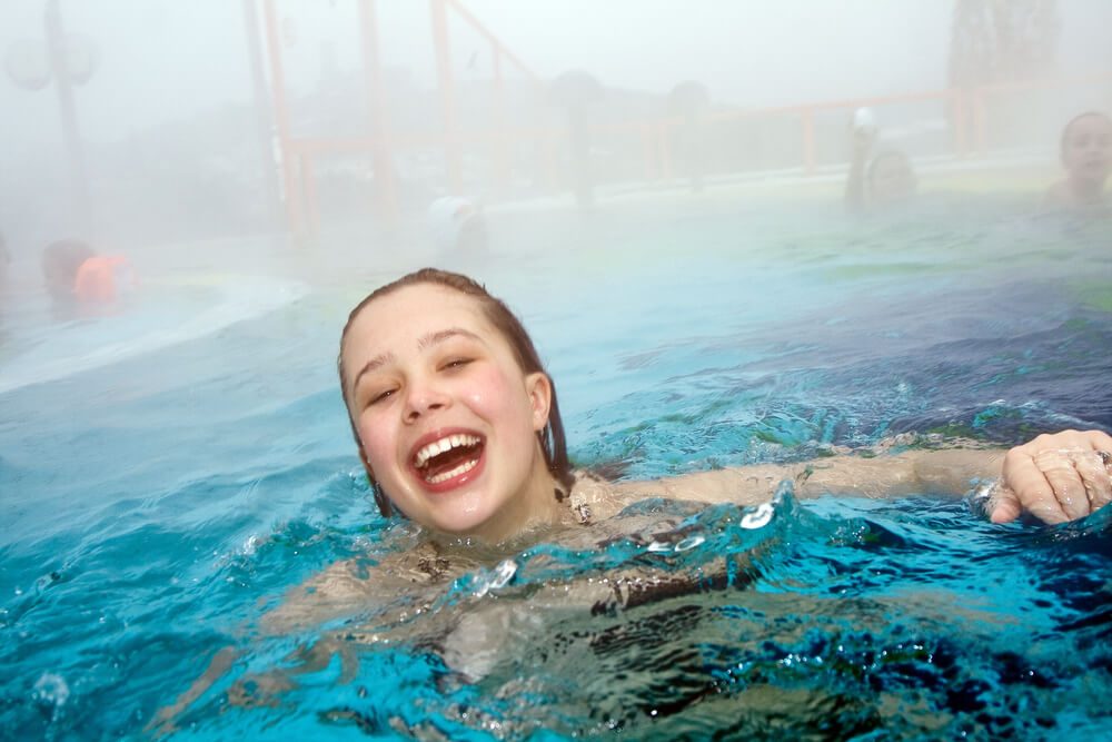 garota sorrindo e nadando na piscina aquecida
